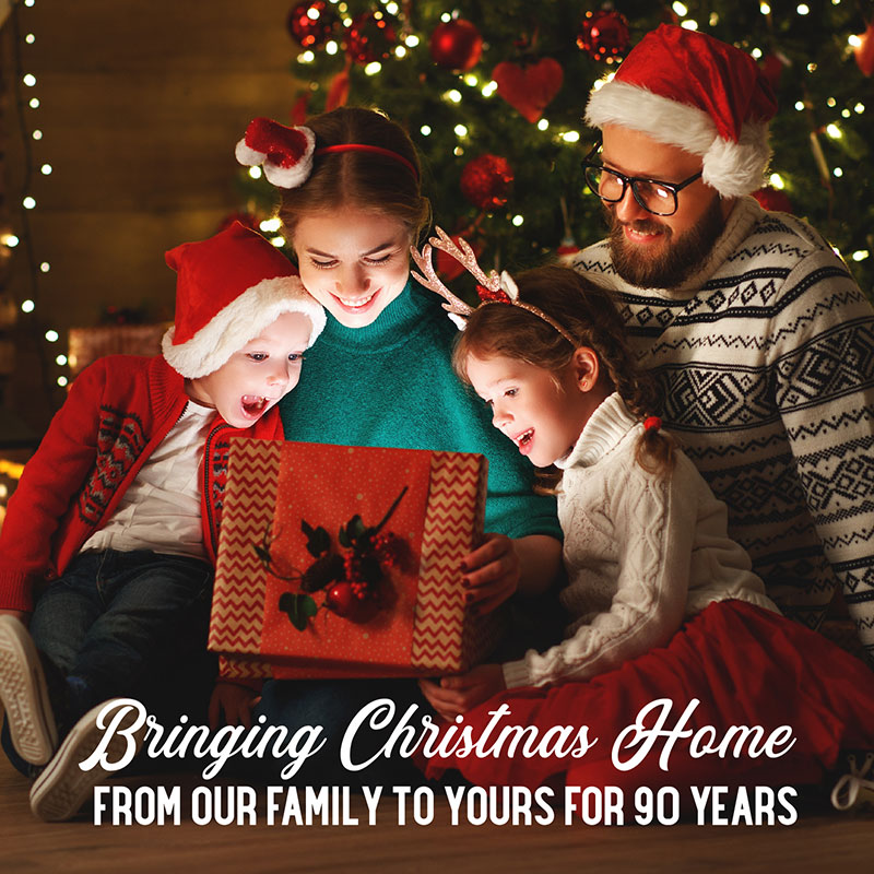 a family opening a christmas gift - bringing christmas home from our family to your for 90 years